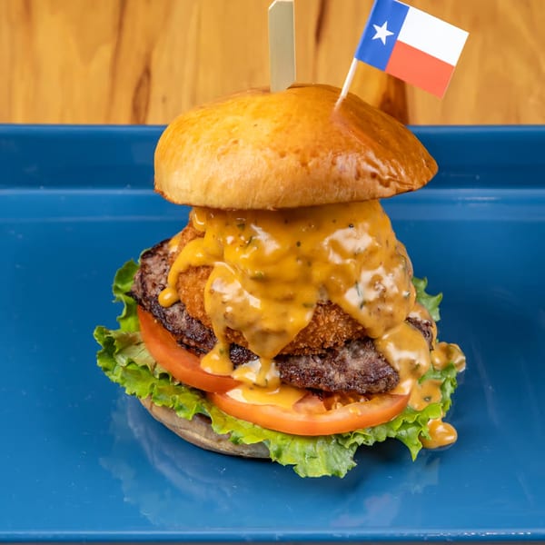 LSA Burger Co. burger with two patties, cheese sauce, lettuce, tomato, and a Texas flag pick.