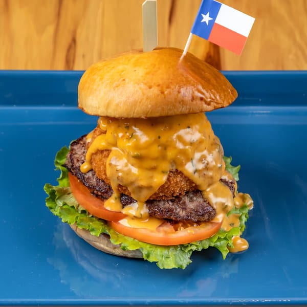 LSA Burger Co.'s Texas burger with a patty, fried onion ring, cheese sauce, lettuce, and tomato.