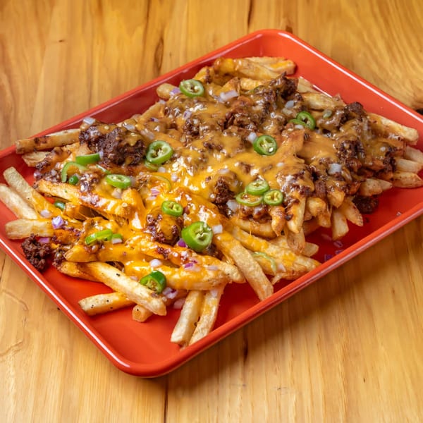LSA Burger Co.'s chili cheese fries, topped with jalapeños and onions, served on a red tray.