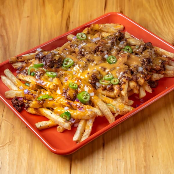 LSA Burger Co. chili cheese fries, topped with jalapeños and red onions, on a red tray.